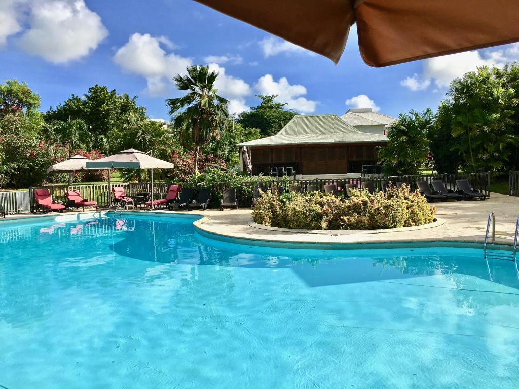 圣弗朗索瓦Résidence Le Vallon Guadeloupe Parc Piscine Appartements & Studios & Services hôteliers à la carte的度假村的游泳池,配有椅子和遮阳伞