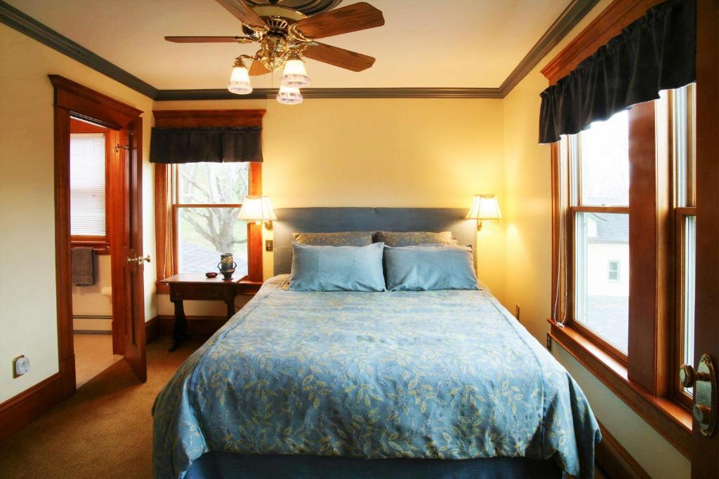 FleischmannsBreezy Hill Inn的一间卧室配有一张蓝色棉被和两个窗户。