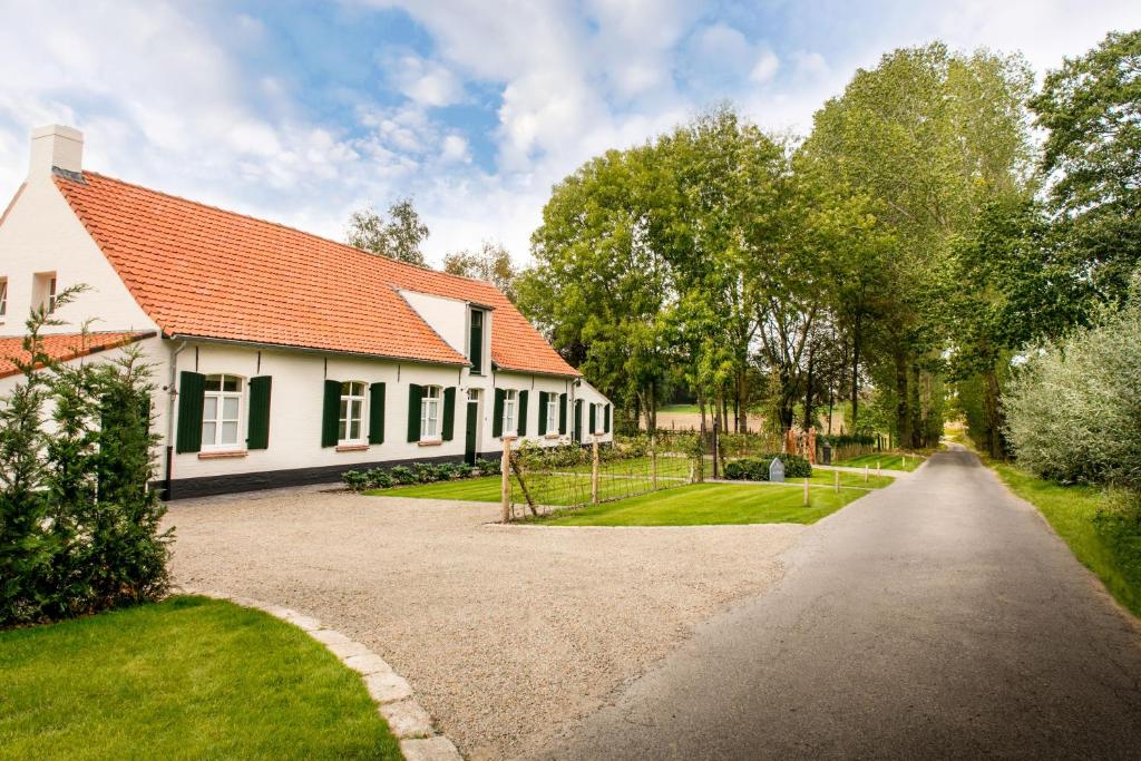伊普尔Cottage de Vinck的白色的房子,有红色的屋顶和车道