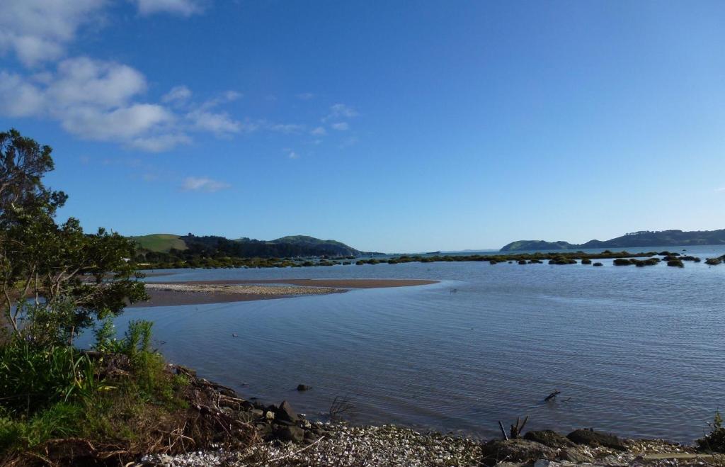 科罗曼德镇Oystercatcher Bay Boathouse的远处有树木的一大片水