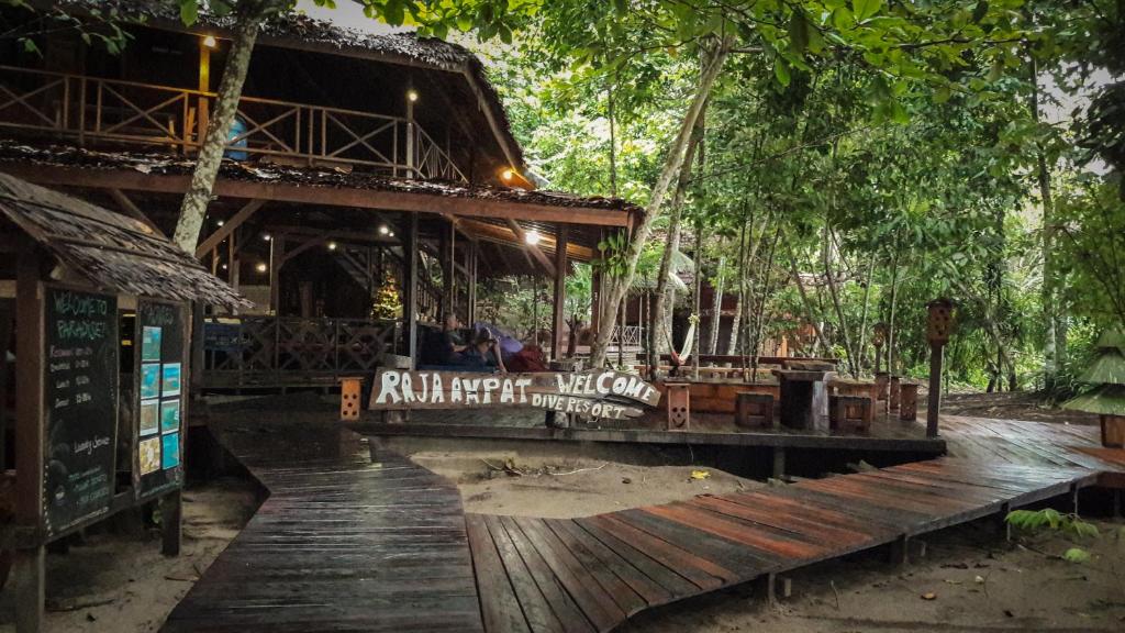 Tapokreng拉贾安帕潜水度假酒店的树木繁茂的建筑前的木甲板