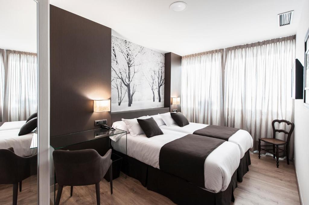 桑坦德Suite Home Sardinero的酒店客房配有两张床和一张书桌
