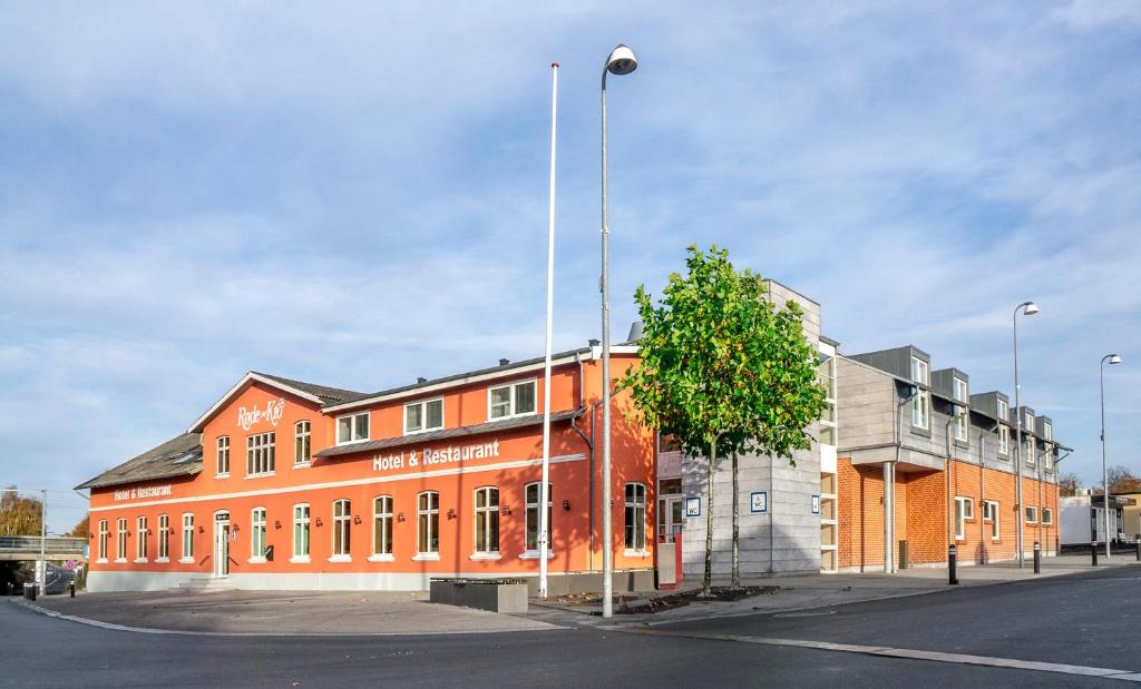 RødekroHotel Røde-Kro的一座橘色的建筑,前面有一棵树
