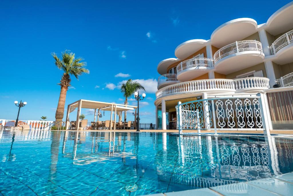 基普塞利阿卡迪亚酒店的棕榈树建筑前的游泳池