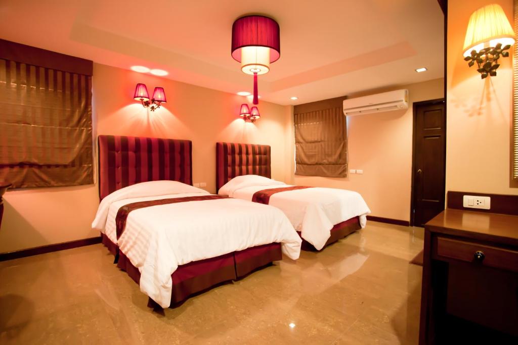 清迈家在清迈的配有粉红色照明的酒店客房内的两张床