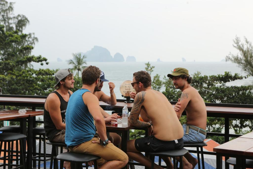 奥南海滩阳台派对旅舍 - 仅限18岁以上的成人入住 的一群坐在海洋前面桌子上的人