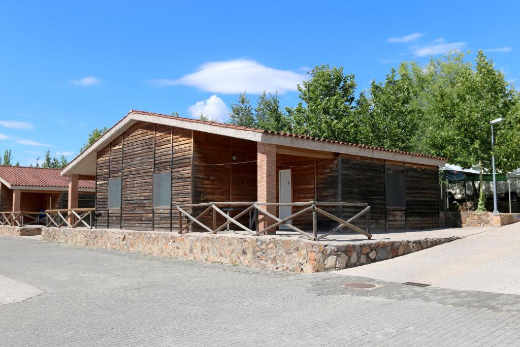 卡塞雷斯Hostal - Bungalows Camping Cáceres的一座带石墙的小木房子