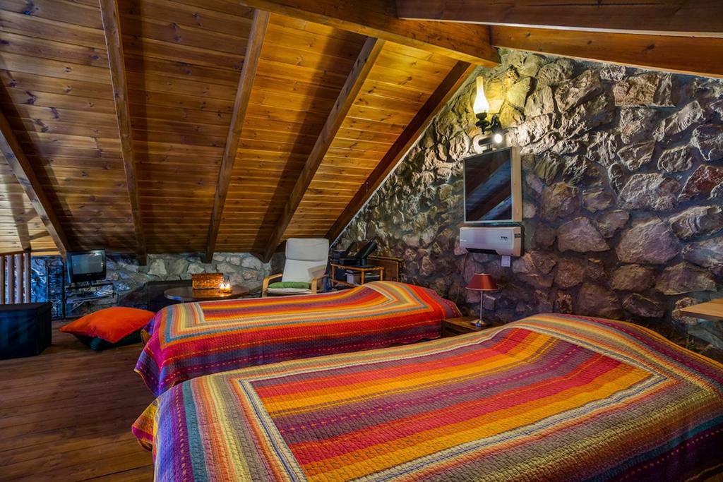 波利兹罗松Naiades Village的一间卧室设有两张床和石墙