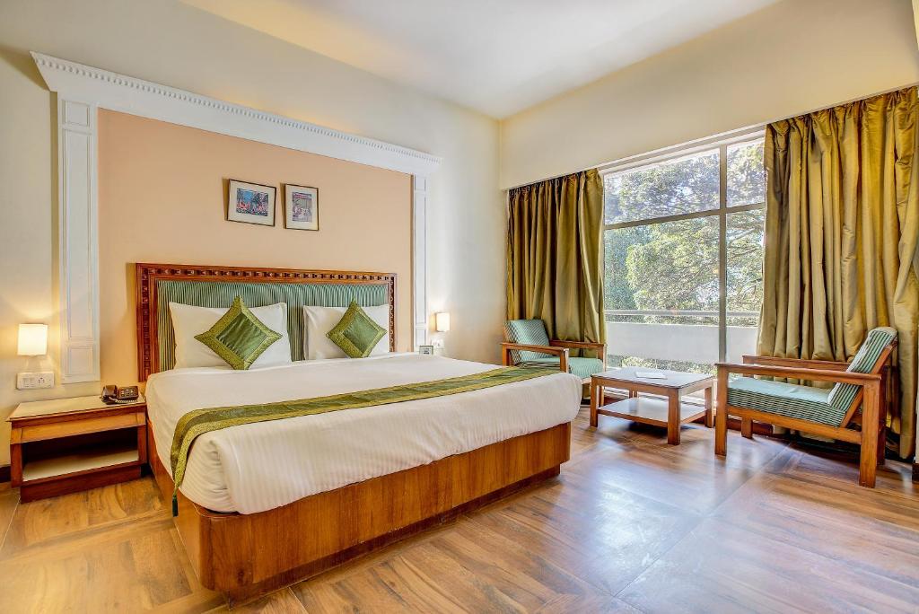 德拉敦Hotel Ajanta Continental的一间卧室设有一张大床和一个大窗户