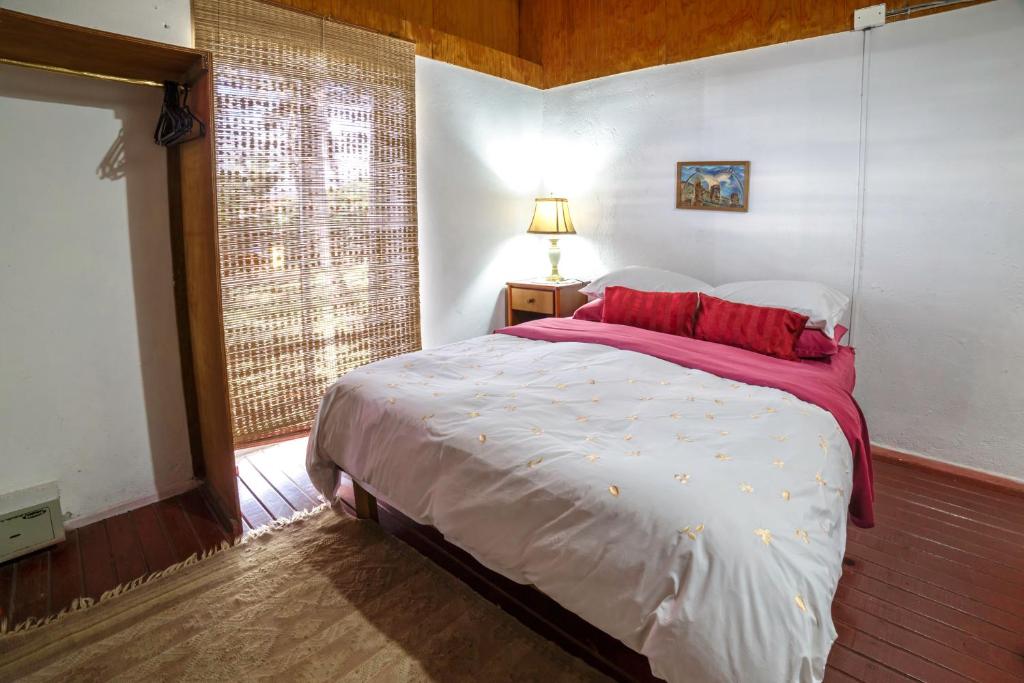 安加罗阿Cabañas Matavai的一间卧室配有一张带红色枕头的床和一扇窗户