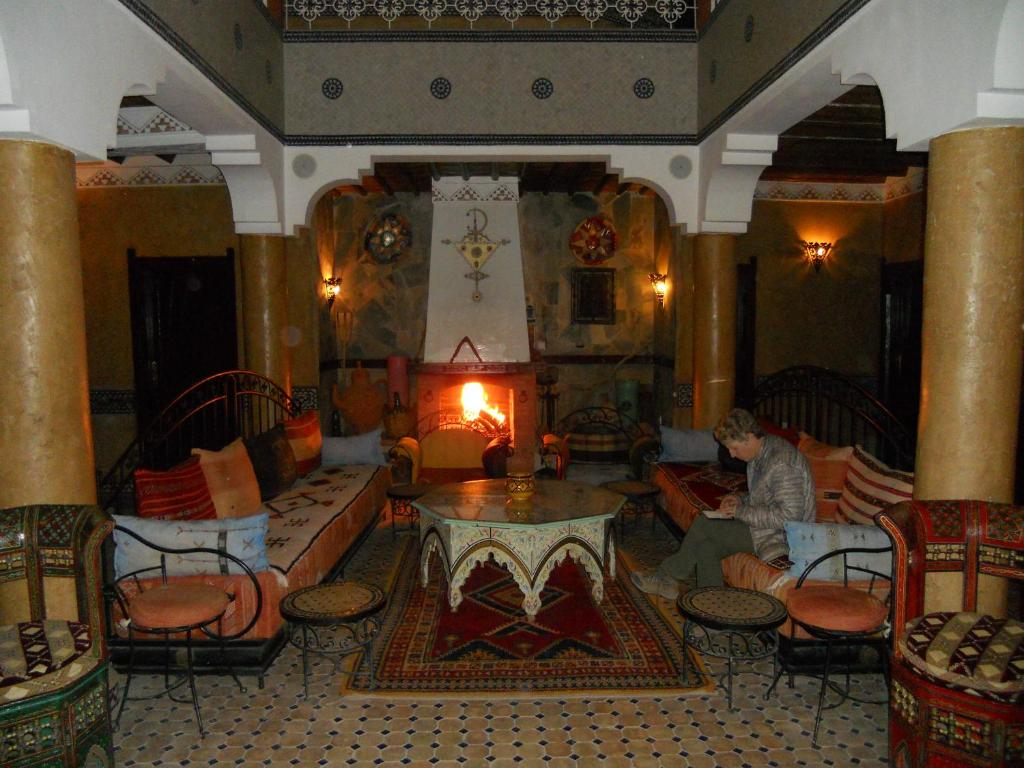 泰夫劳特Hotel Salama STE SAL- AMA SUD SARL AU的坐在带壁炉的客厅里的人