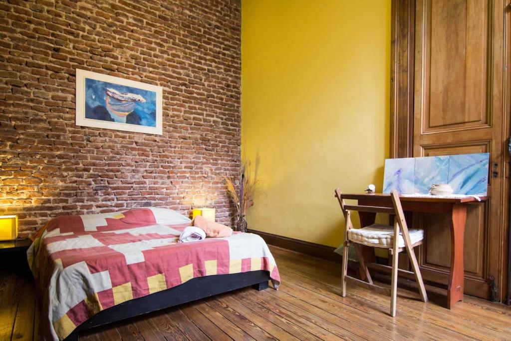 蒙得维的亚casa vegana的一间卧室配有一张床、一张桌子和砖墙
