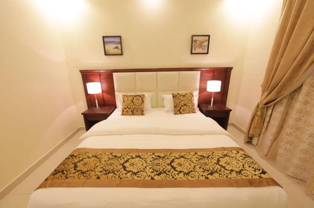 阿尔阿尔Lara Al Jawf Hotel Apartments的一间卧室配有一张大床和两盏灯