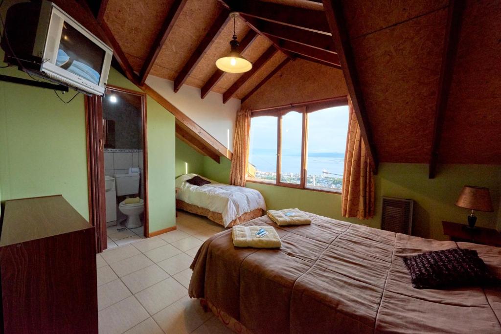 乌斯怀亚Mirador del Beagle Hosteria的一间带两张床的卧室和一间带窗户的浴室