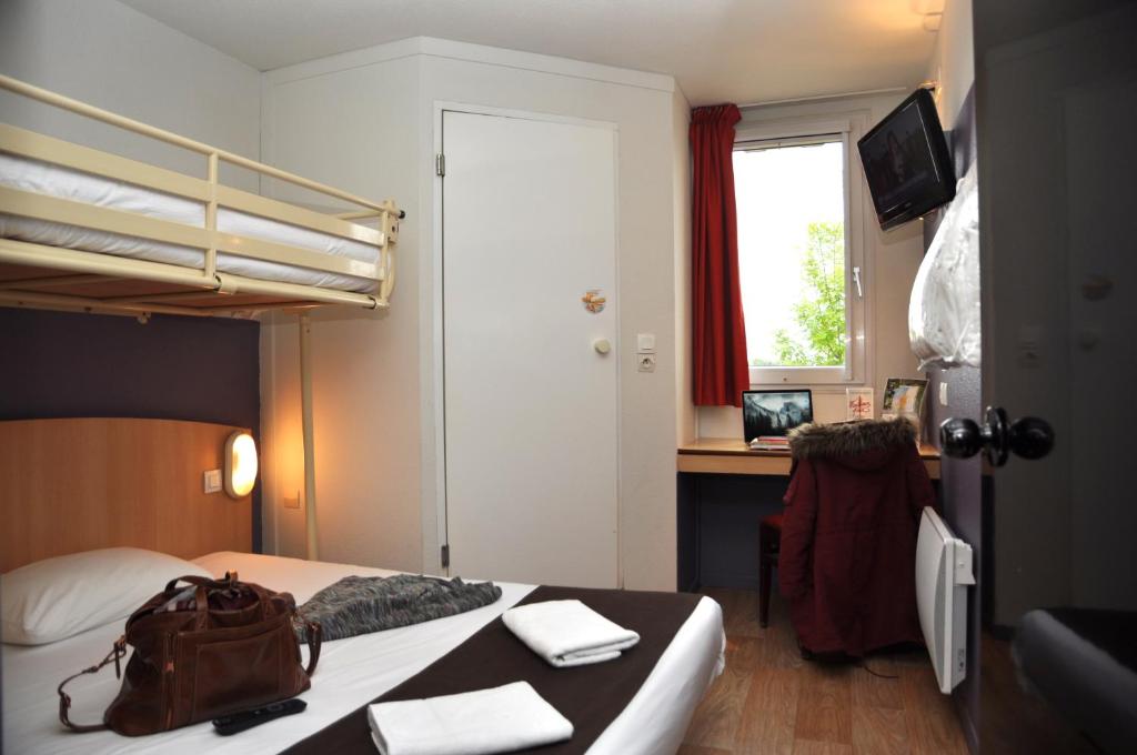 尼奥尔普瑞米尔尼奥特伊斯特夏雷经典酒店的一间卧室配有一张床和一张带袋子的书桌