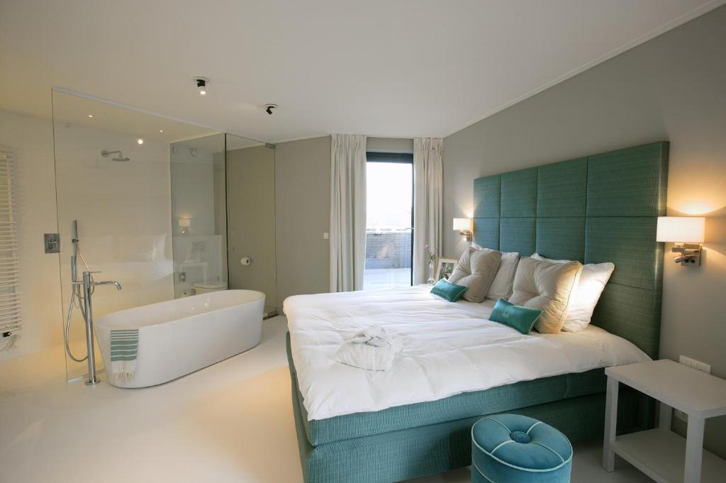 梅赫伦VixX套房酒店的一间卧室设有一张大床和一个浴缸