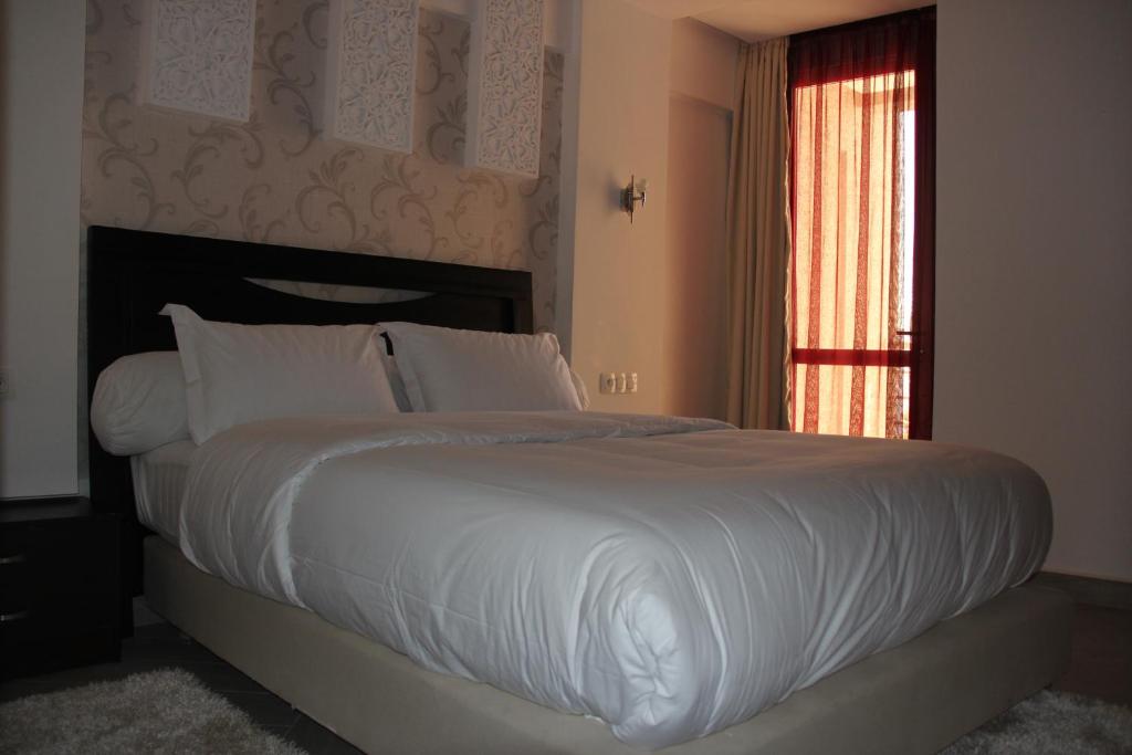 阿尤恩Résidence La Place的卧室配有一张带白色床单的大床和窗户。