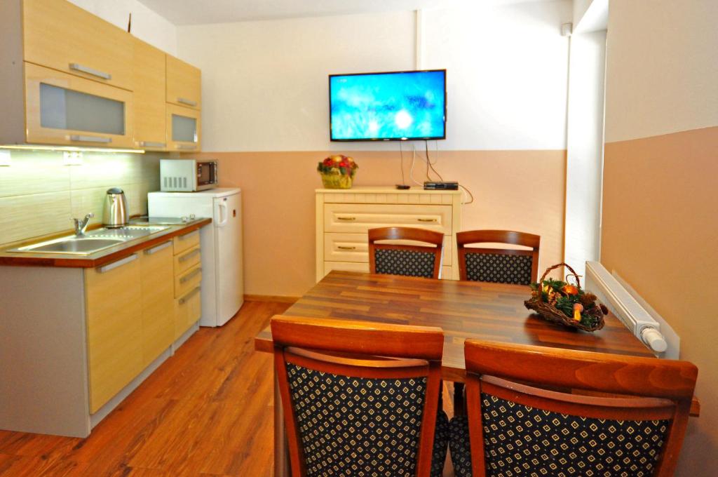 迪马诺卡多林纳Apartment Bartek Ski Rental的厨房配有木桌和墙上的电视。