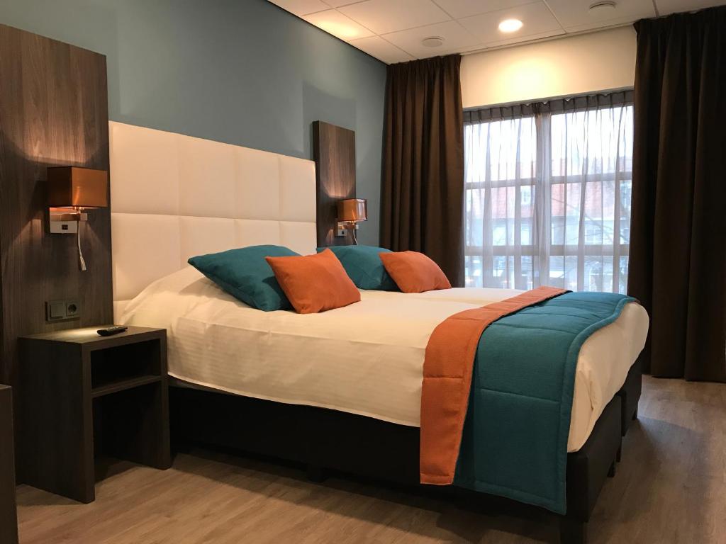 斯鲁伊斯Rivers Hotel的一间卧室配有一张带橙色和蓝色枕头的大床