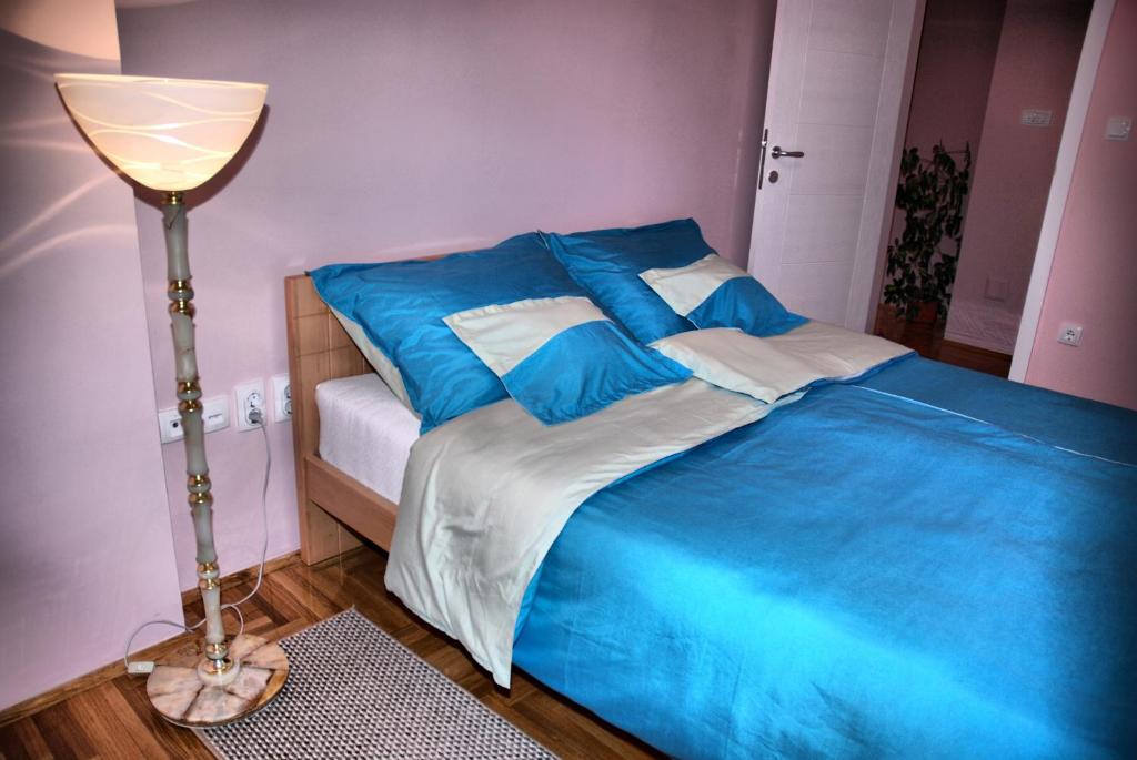 松博尔Apartman Milkovic 2的一间卧室配有一张带蓝色床单和一盏灯的床。