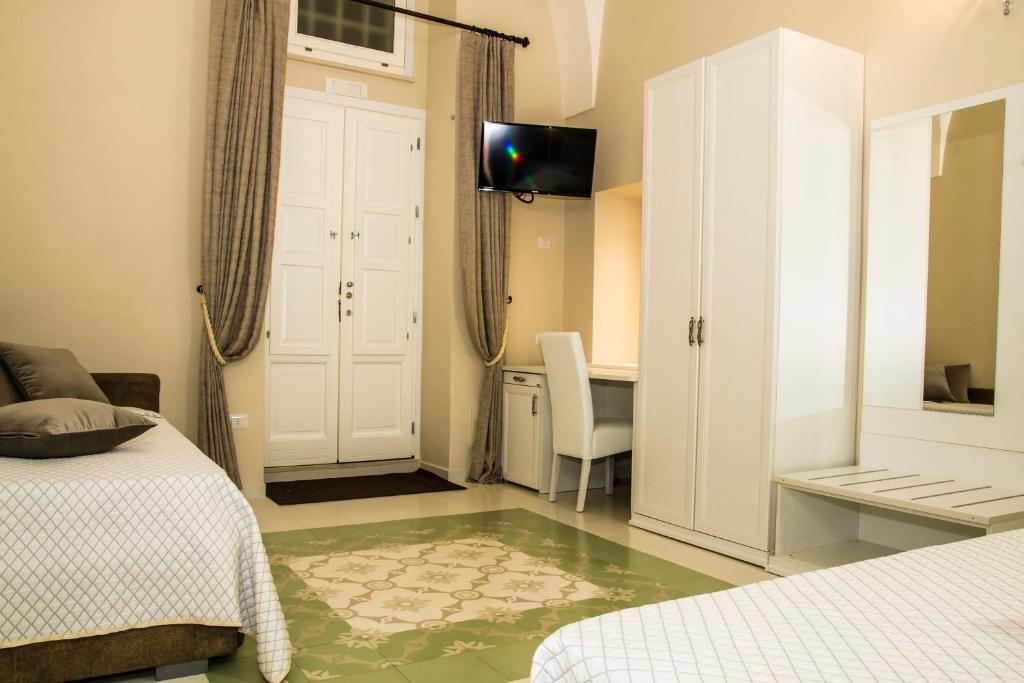 格拉维纳普利亚Stanze Orsini的一间卧室配有两张床、一张桌子和一台电视。