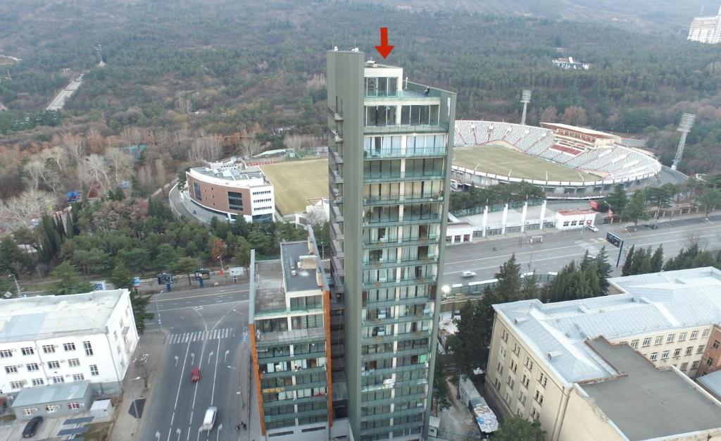 第比利斯Full Comfort Apartment at Chavchavadze的一座高大的建筑,上面有红箭
