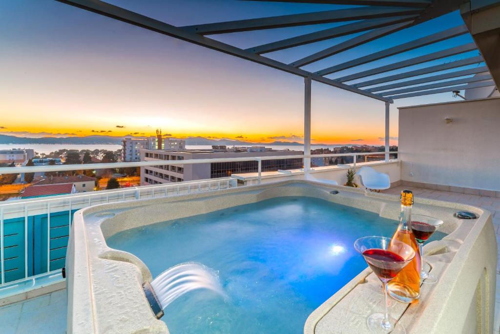 扎达尔Sunset Penthouse Apartment with Jacuzzi and Seaview的一座建筑物屋顶上的游泳池,上面有酒杯