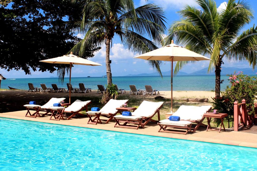波普托The Waterfront Hotel at Fishermans Village的海滩旁的游泳池配有椅子和遮阳伞
