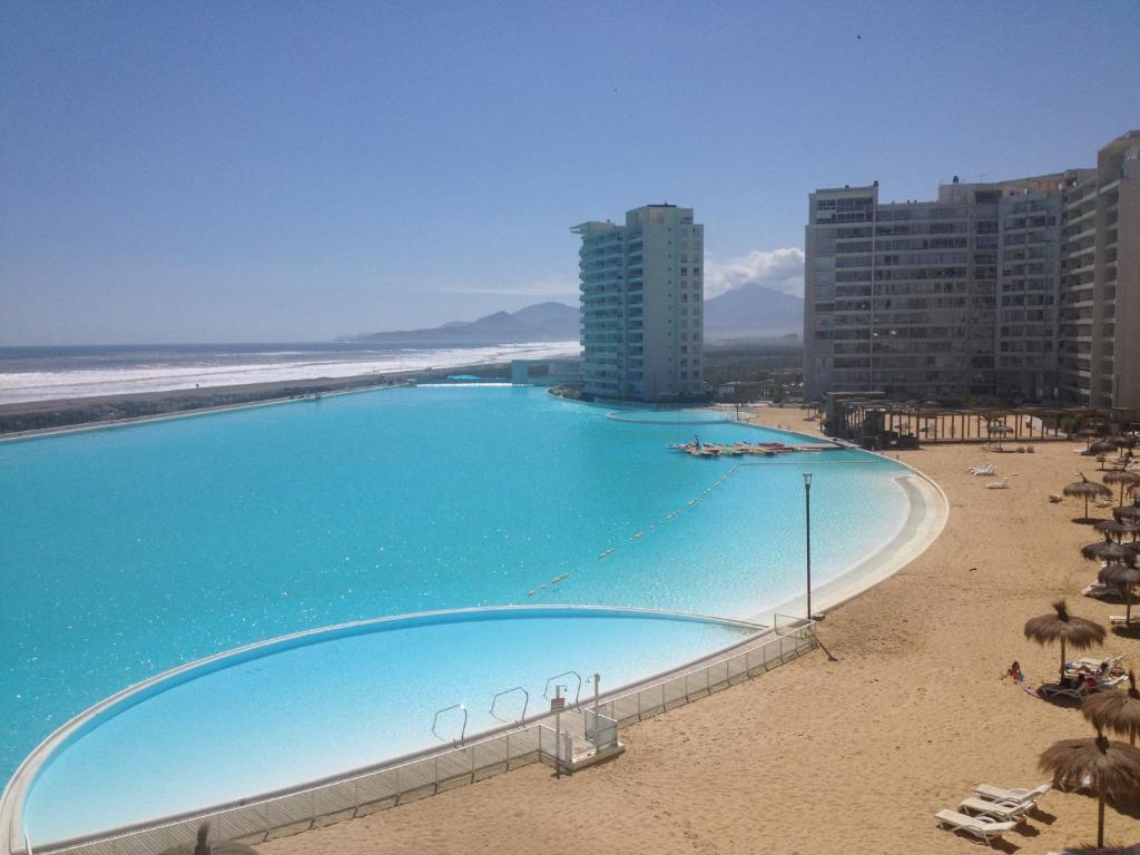 拉塞雷纳Departamento Resort Laguna del Mar的海滩旁的大型游泳池,配有遮阳伞