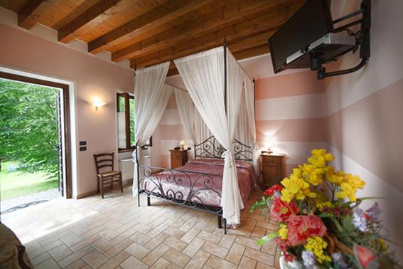 蒙赞巴诺Corte Fattori的一间卧室,卧室里配有天蓬床和鲜花