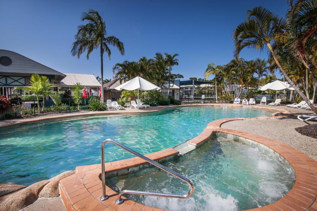 努萨维尔Ivory Palms Resort Noosa的一座拥有蓝色海水和棕榈树的大型游泳池