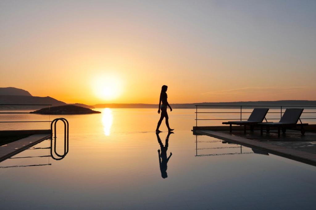 阿尔米里达SK Place Luxury Seafront Villas Chania的背着日落在水面上行走的人