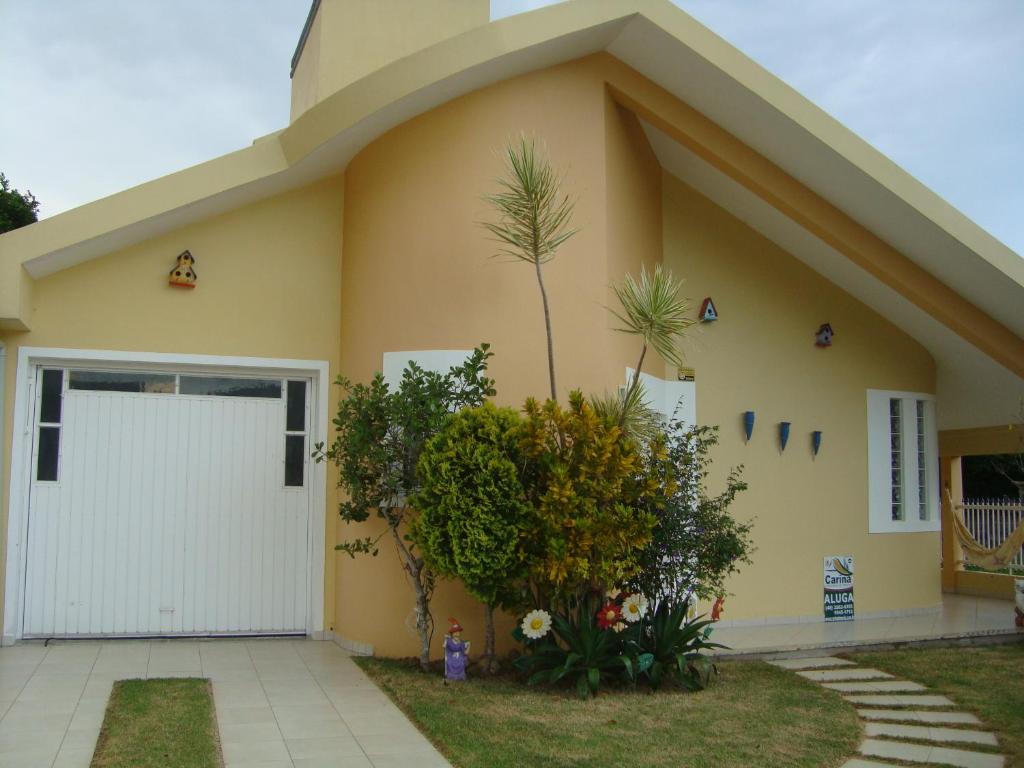 塞尔苏拉穆斯州长镇Casa de Praia em Palmas的一座黄色的小房子,设有白色车库