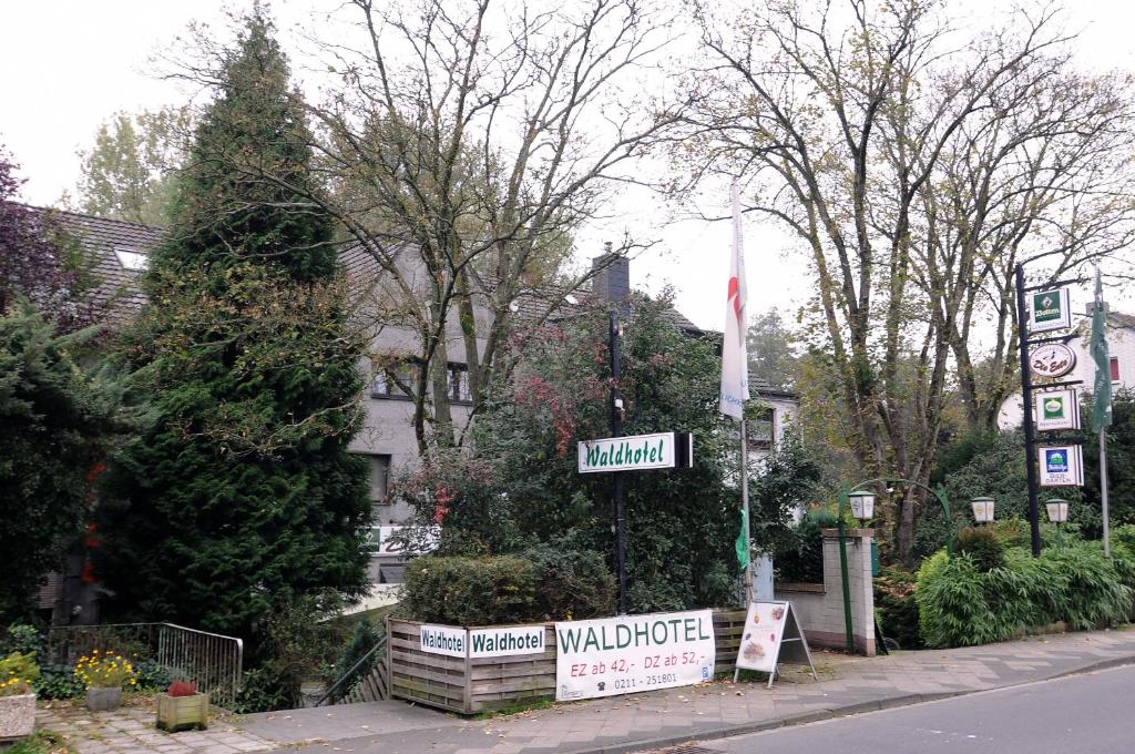 杜塞尔多夫乌特巴赫沃尔德酒店的树木繁茂的院子前的街道标志