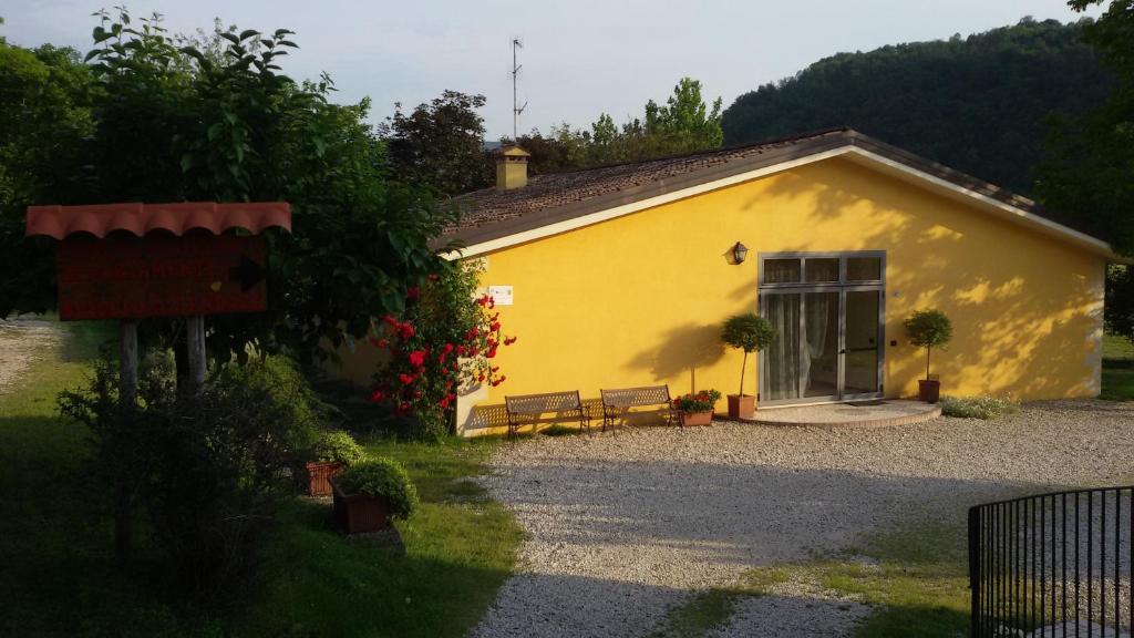 奥卡纳诺Agriturismo Il Lago的前面有两长椅的黄色建筑