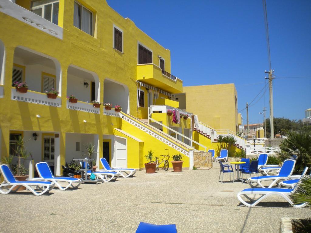 兰佩杜萨Hotel Mare Blu的前面有蓝色躺椅的黄色建筑