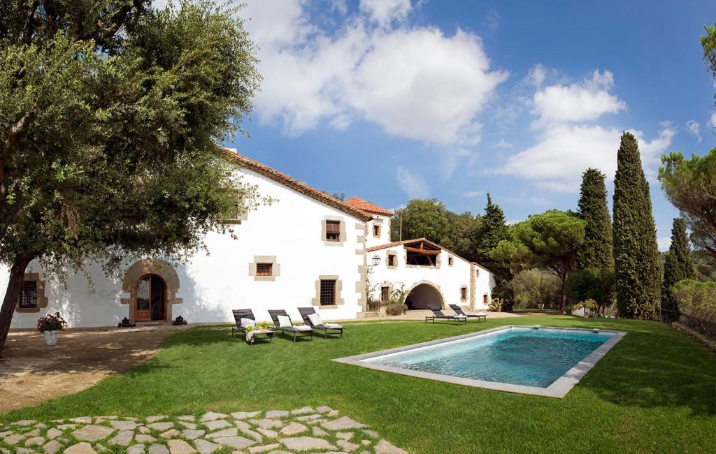 圣安德烈斯-德利亚瓦内拉斯Masia Santa Mónica的一座白色的房子,在庭院里设有一个游泳池