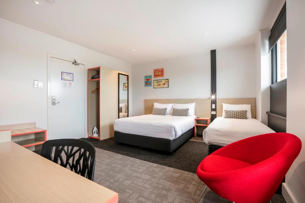 布里斯班奈特卡普坎普希尔酒店的酒店客房,设有两张床和一张红色椅子