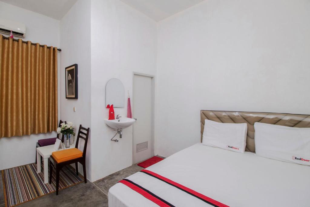 雅加达红门旅馆 @ 拉迪奥达拉姆的白色卧室设有床铺和水槽