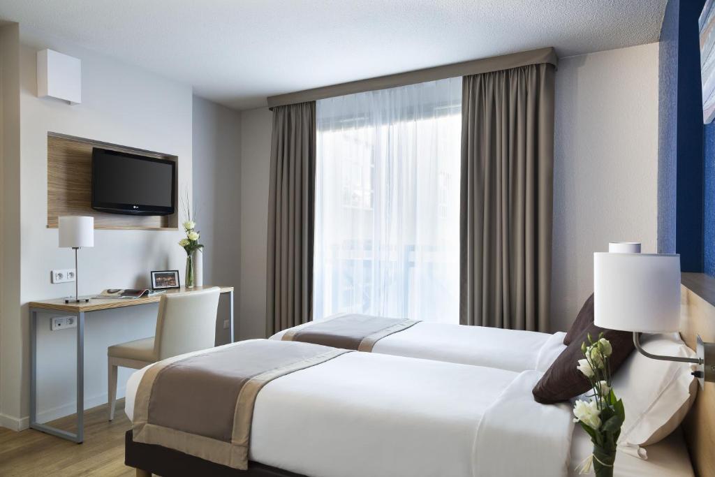 马赛馨乐庭马赛普拉多侠诺酒店的酒店客房设有两张床、一张书桌和一个窗户。