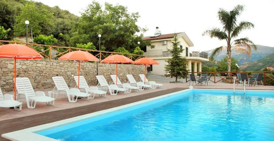 弗兰卡维拉迪西奇利亚La Parrinara的一座带椅子和遮阳伞的游泳池位于一座建筑旁边