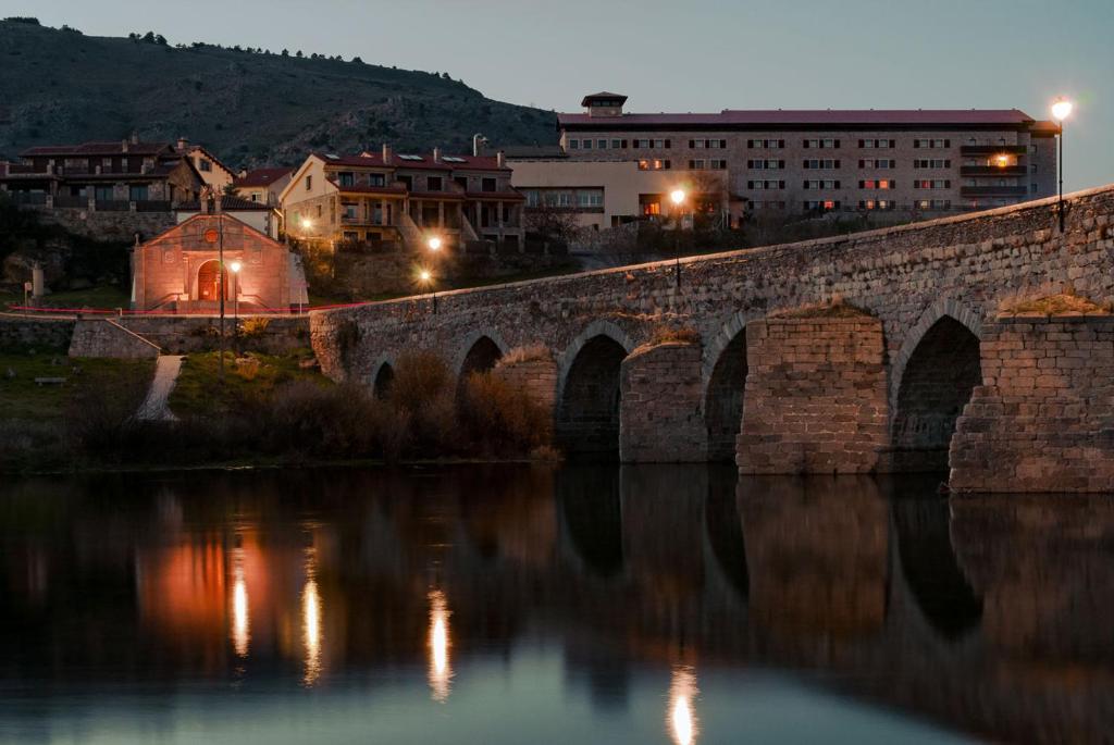 埃尔巴科-德阿维拉Hospedium Hotel Mirador de Gredos的一条古老的石桥,晚上在河上