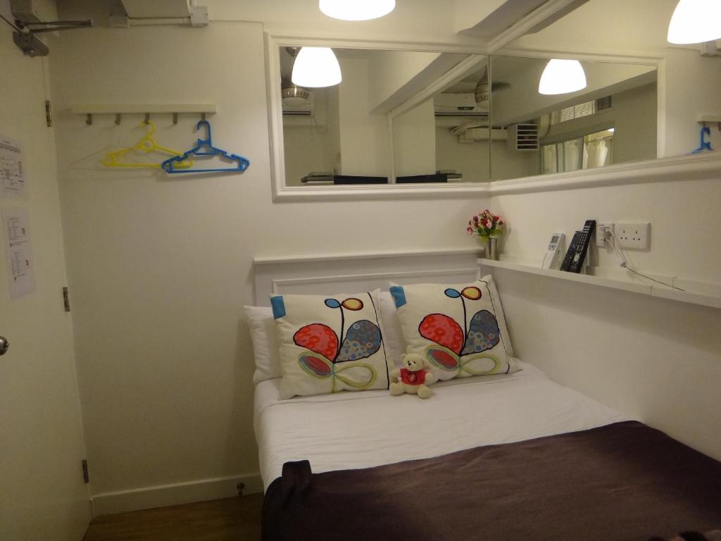 香港Apple lnn Causeway Bay的客房配有带2个枕头和镜子的床