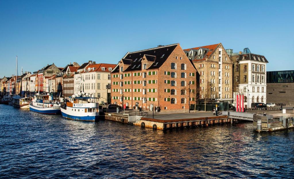 哥本哈根新港71号酒店的一群船停靠在河里,有建筑物