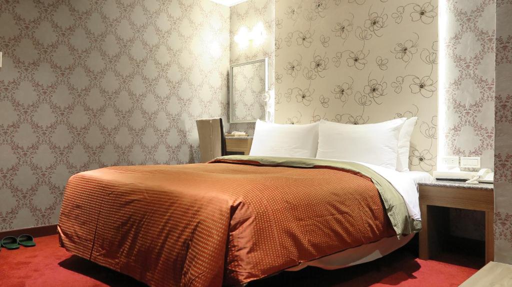 台北一等好旅店的一间卧室配有一张带橙色毯子的床