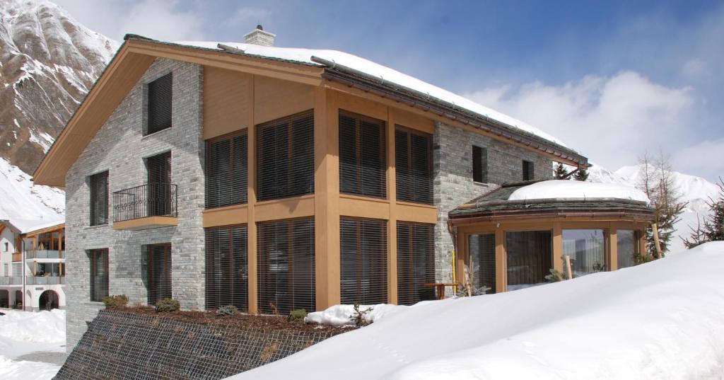 萨姆瑙恩Grischuna Mountain Lodge的山前雪中的房子