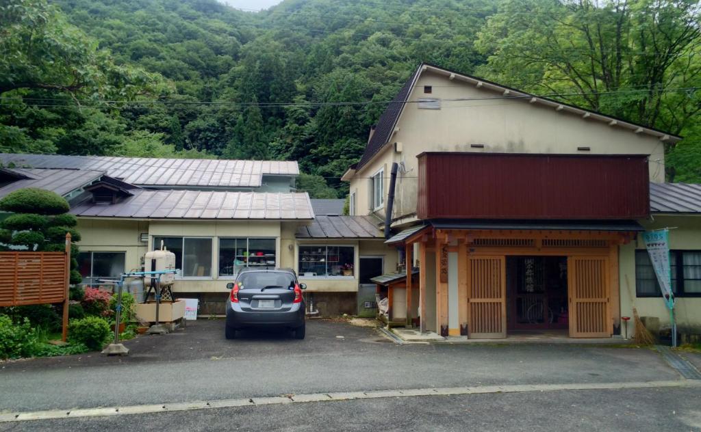雫石町荣弥温泉民宿的停在房子前面的停车场的汽车