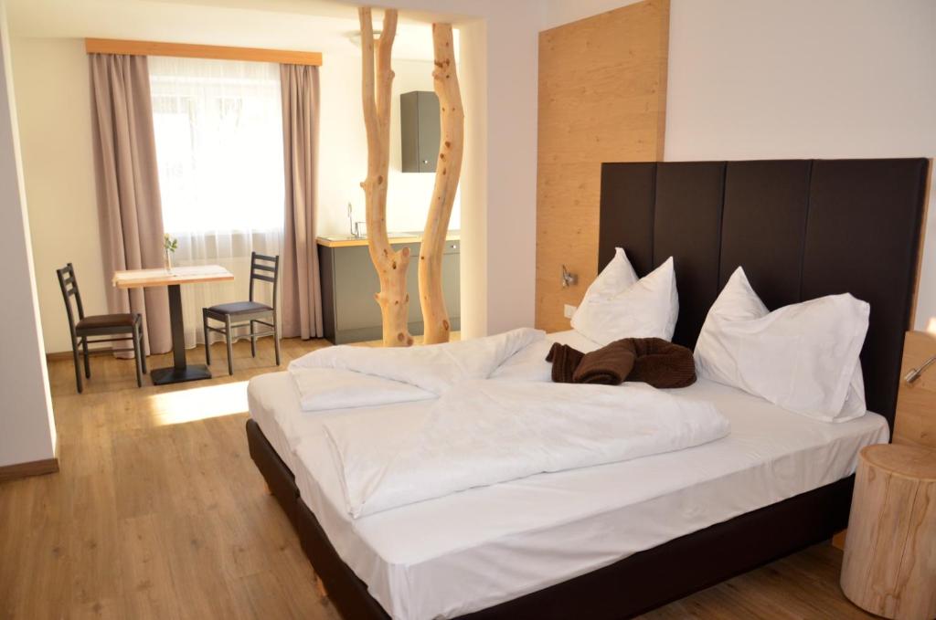 埃尼亚Guesthouse Dolomiten的卧室配有一张白色大床和木制床头板