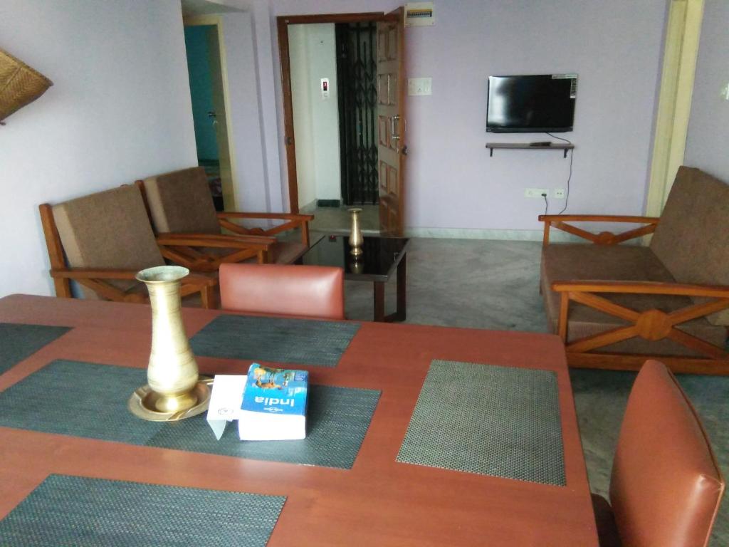 加尔各答Nalanda Tulip的客厅配有桌椅和电视。