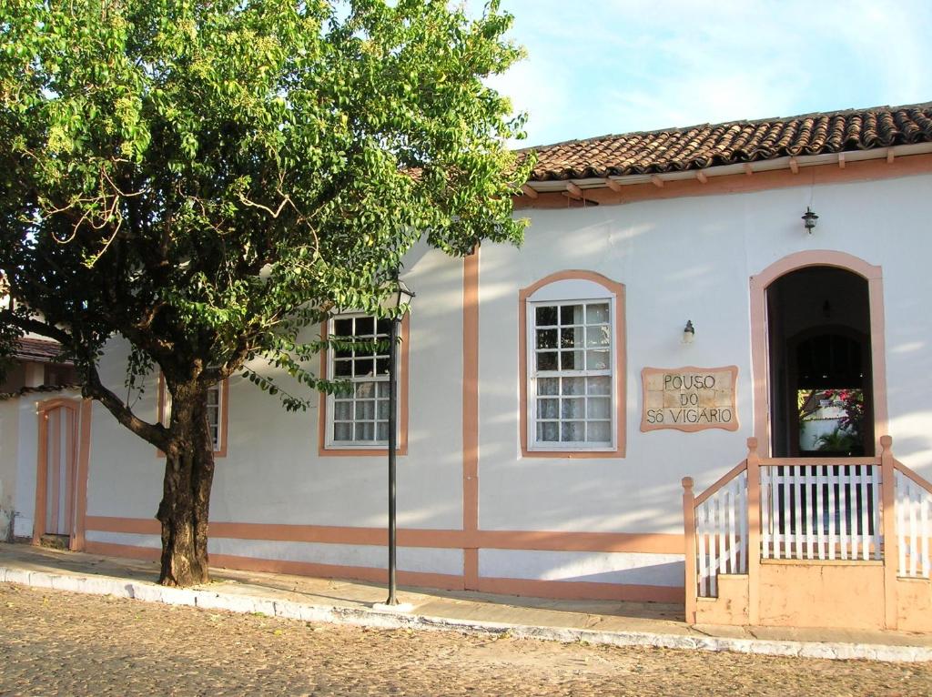 皮雷诺波利斯Pousada Pouso do Sô Vigario的前面有一棵树的白色小建筑
